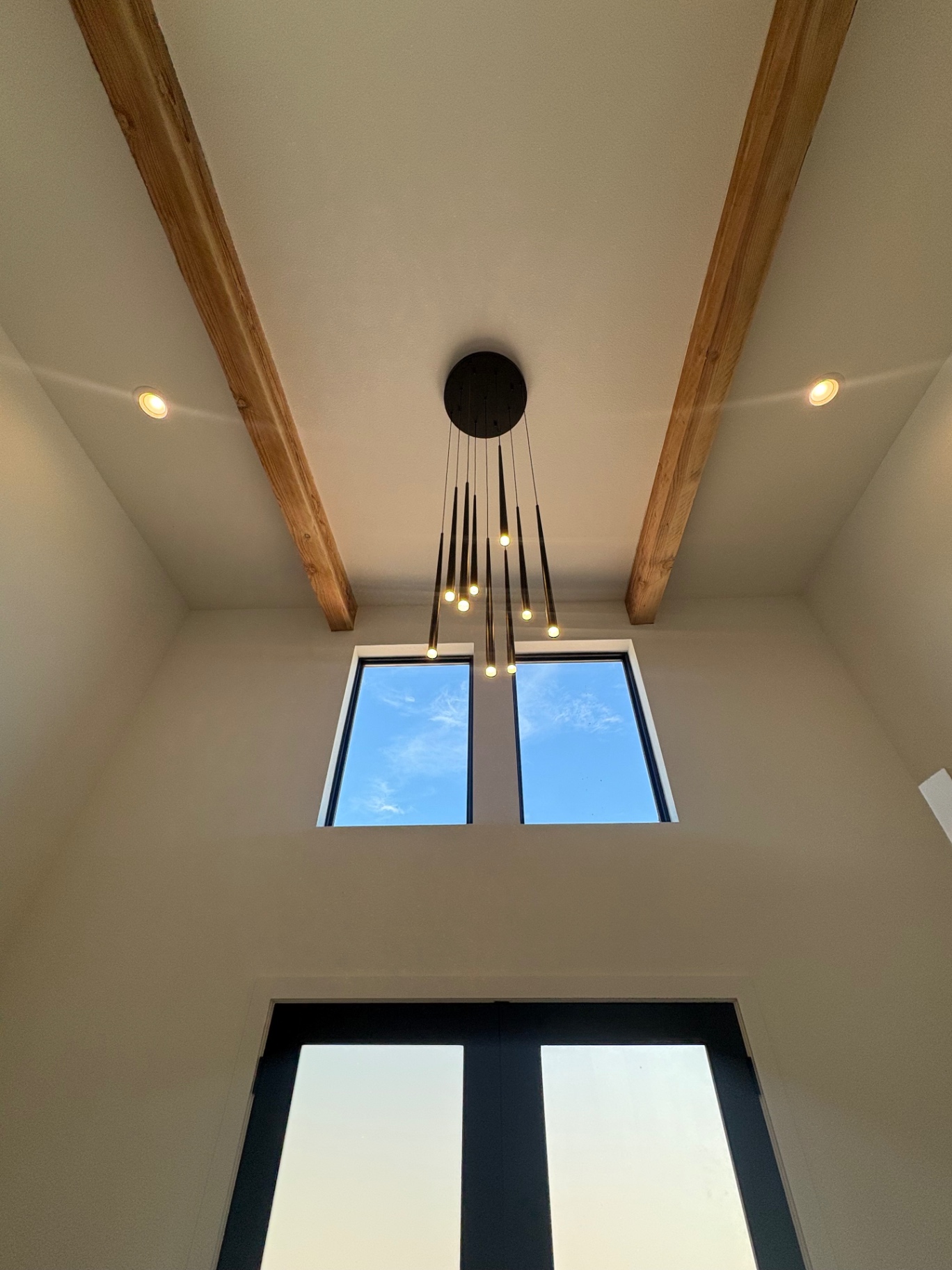Two-story entry with exposed timber beams, clerestory windows and cascading pendant chandelier