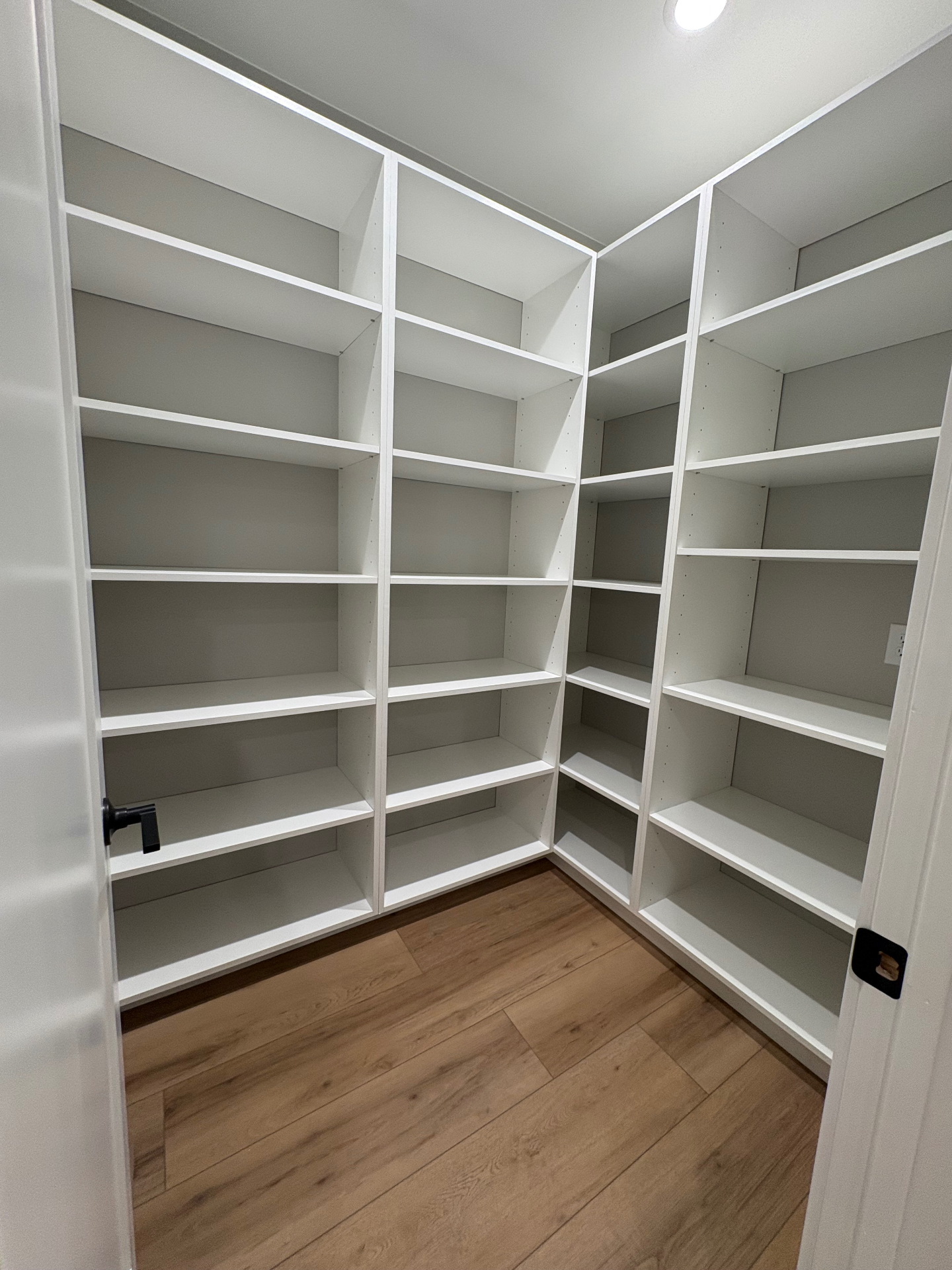 Walk-in pantry with custom floor-to-ceiling white shelving