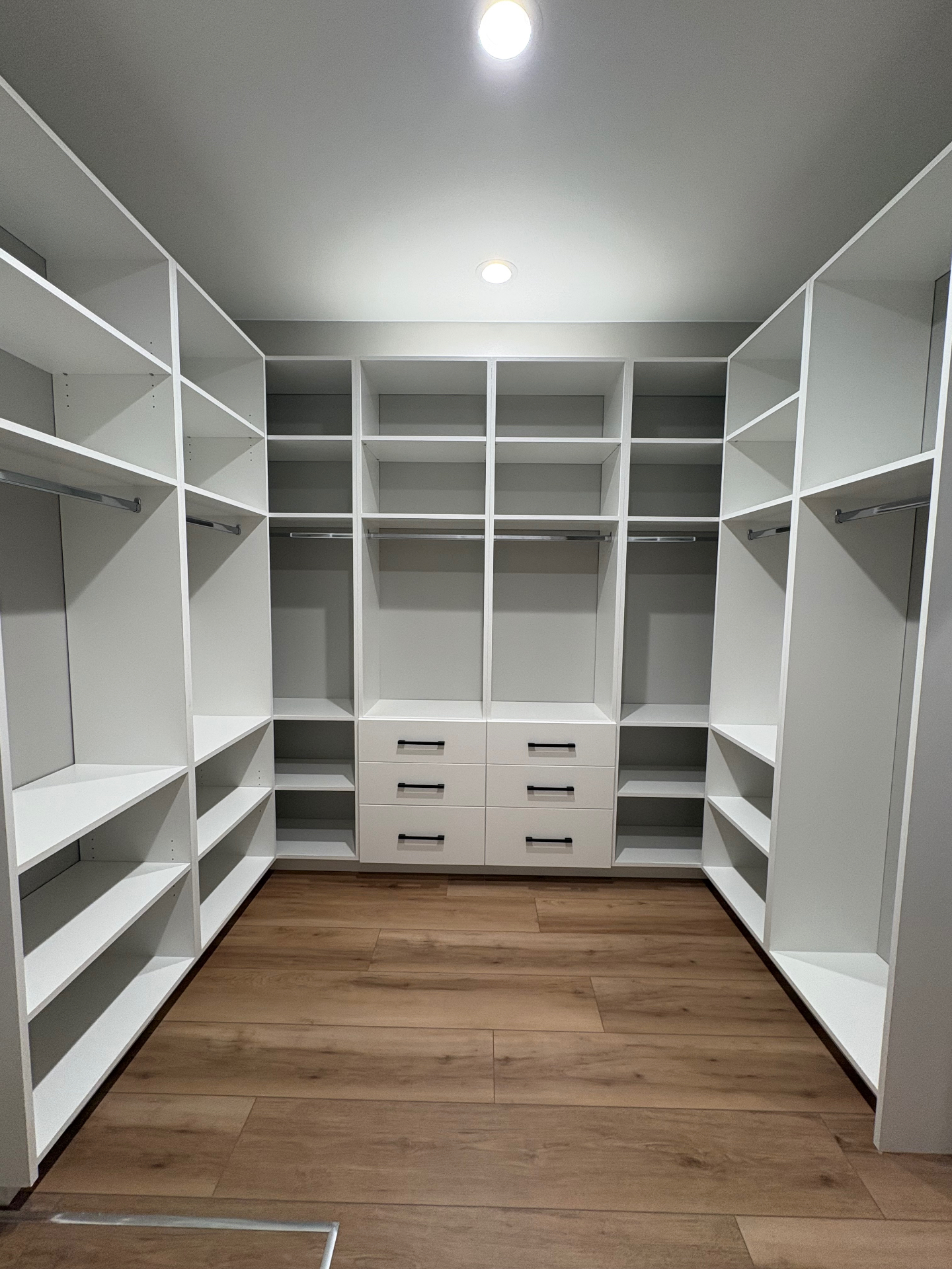 Custom walk-in closet with white shelving, hanging space and integrated drawers