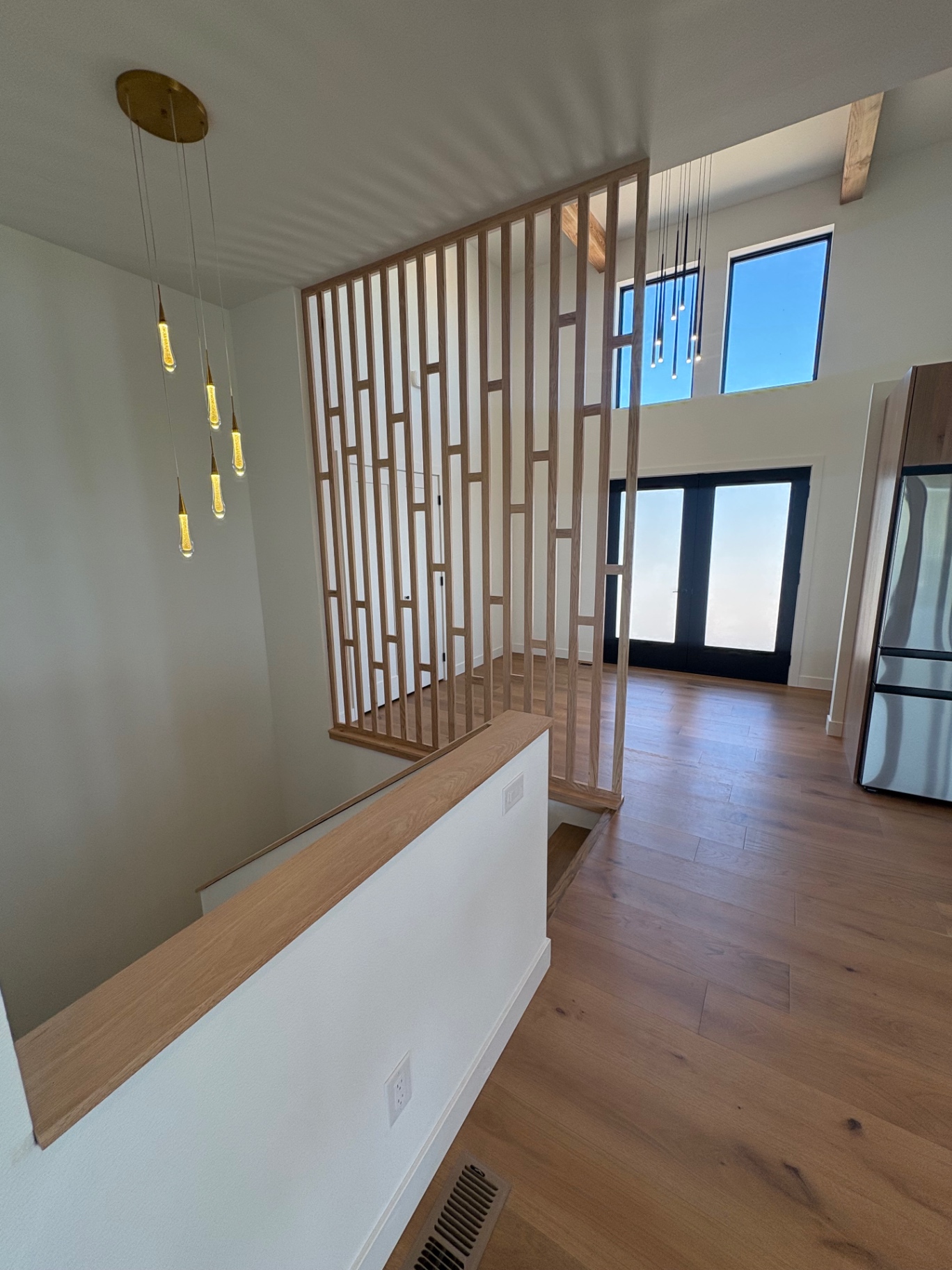 Custom oak slat partition framing the entry with timber beams and pendant cluster
